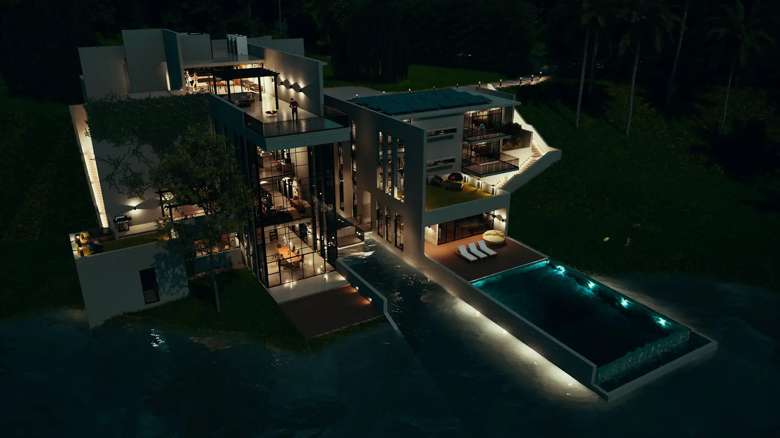 Aerial night view: the same composition lit from within, infinity pool glowing, south-facing terraces and bedrooms warm against the dark hill