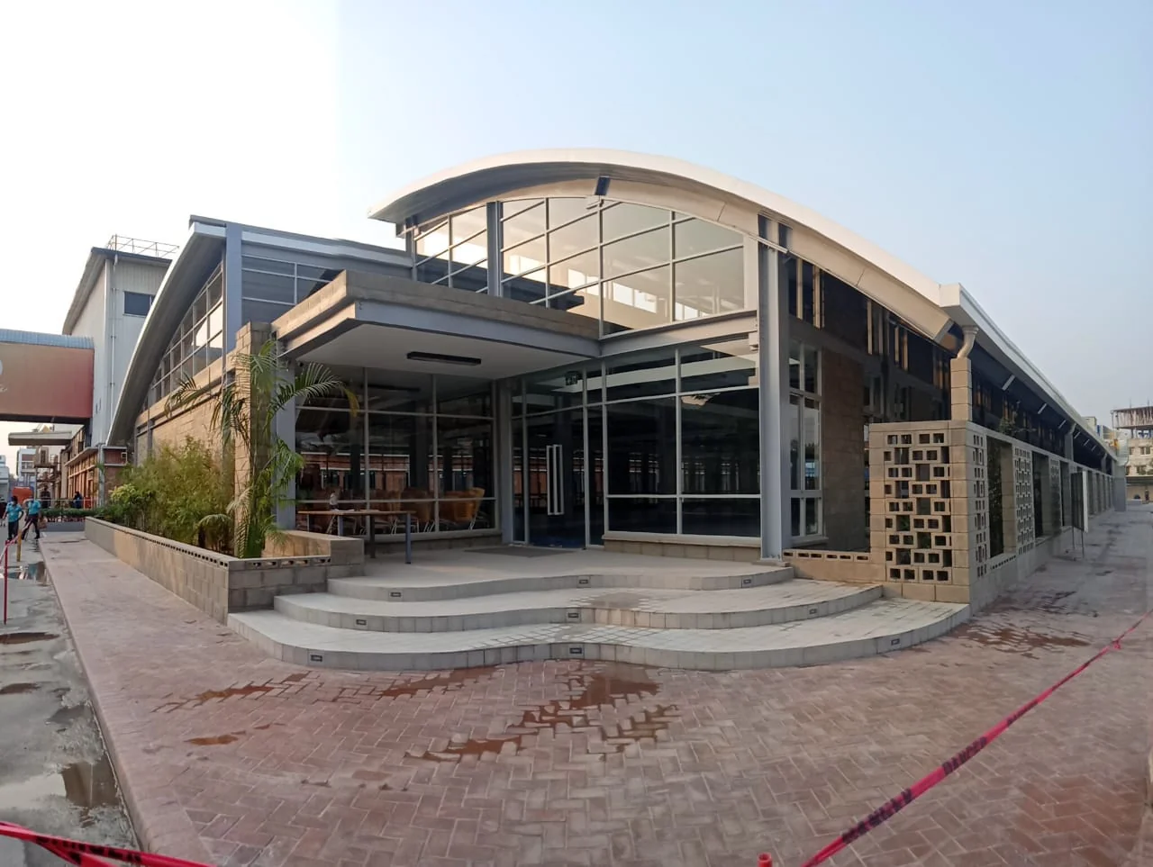 Canteen as-built: entrance facade at dusk, curved steps and landscaping