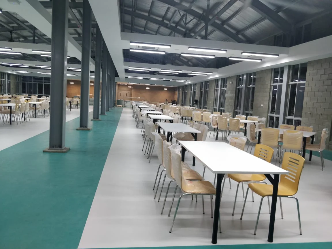 Canteen interior as-built: dining hall at completion, turquoise floor and timber chairs