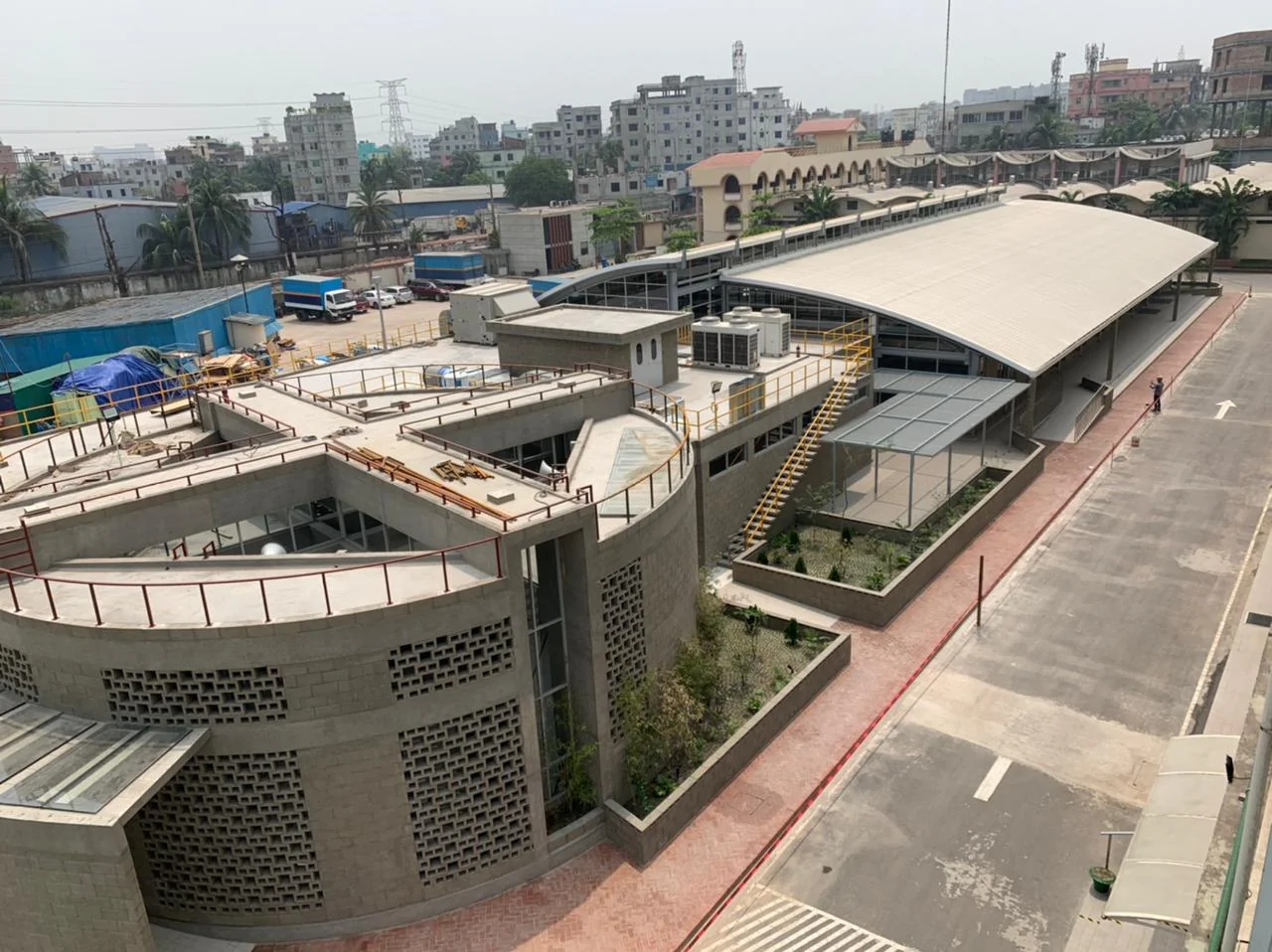 Mosque as-built: aerial view of the circular mosque volumes from above, Dhaka skyline beyond
