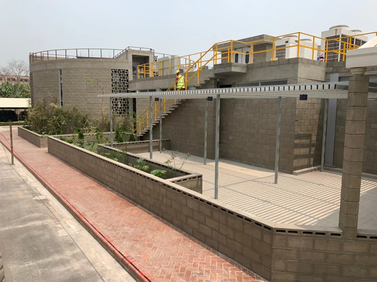 Mosque as-built: rear court with steel pergola, yellow-railed external stair, lattice walls and planted beds