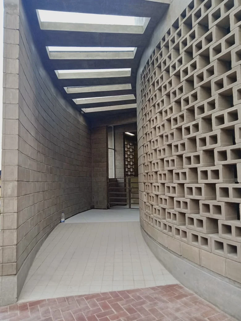 Mosque as-built: entry corridor between inner and outer walls, skylights above, lattice casting light