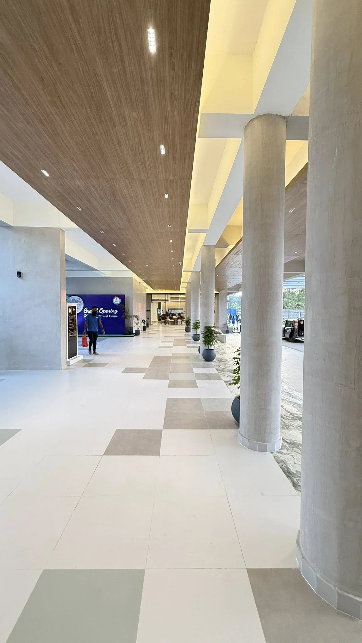 The lobby on grand-opening day: the long concourse with the AWT Rest House welcome banner at the far end, columns and floor in tile pattern, soft cove lighting