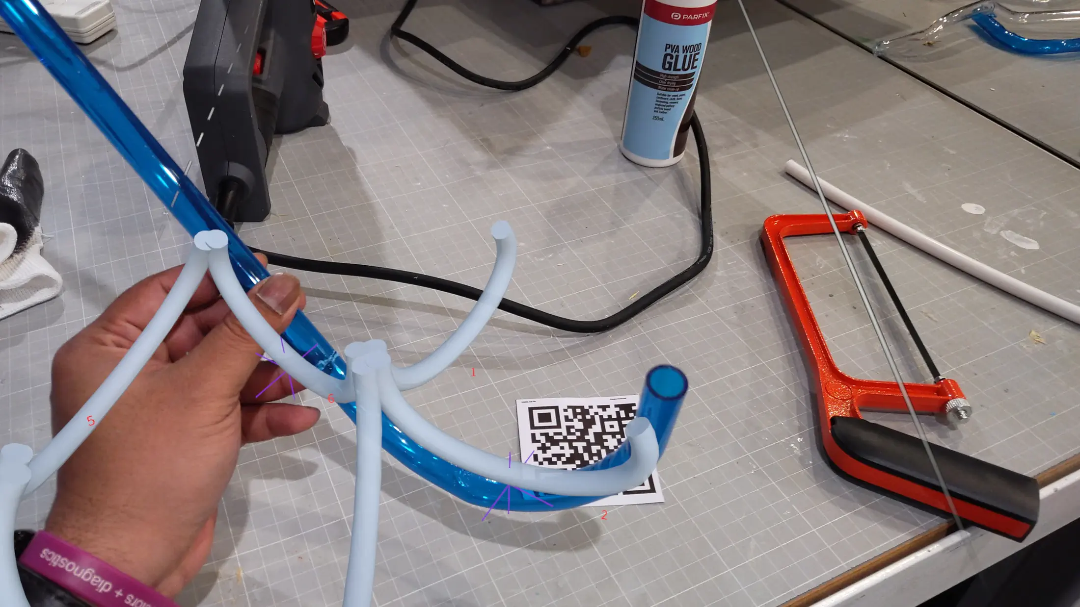 HoloLens capture: AR overlay projected onto workspace, holographic guides indicating tube positions and orientations at the start of assembly