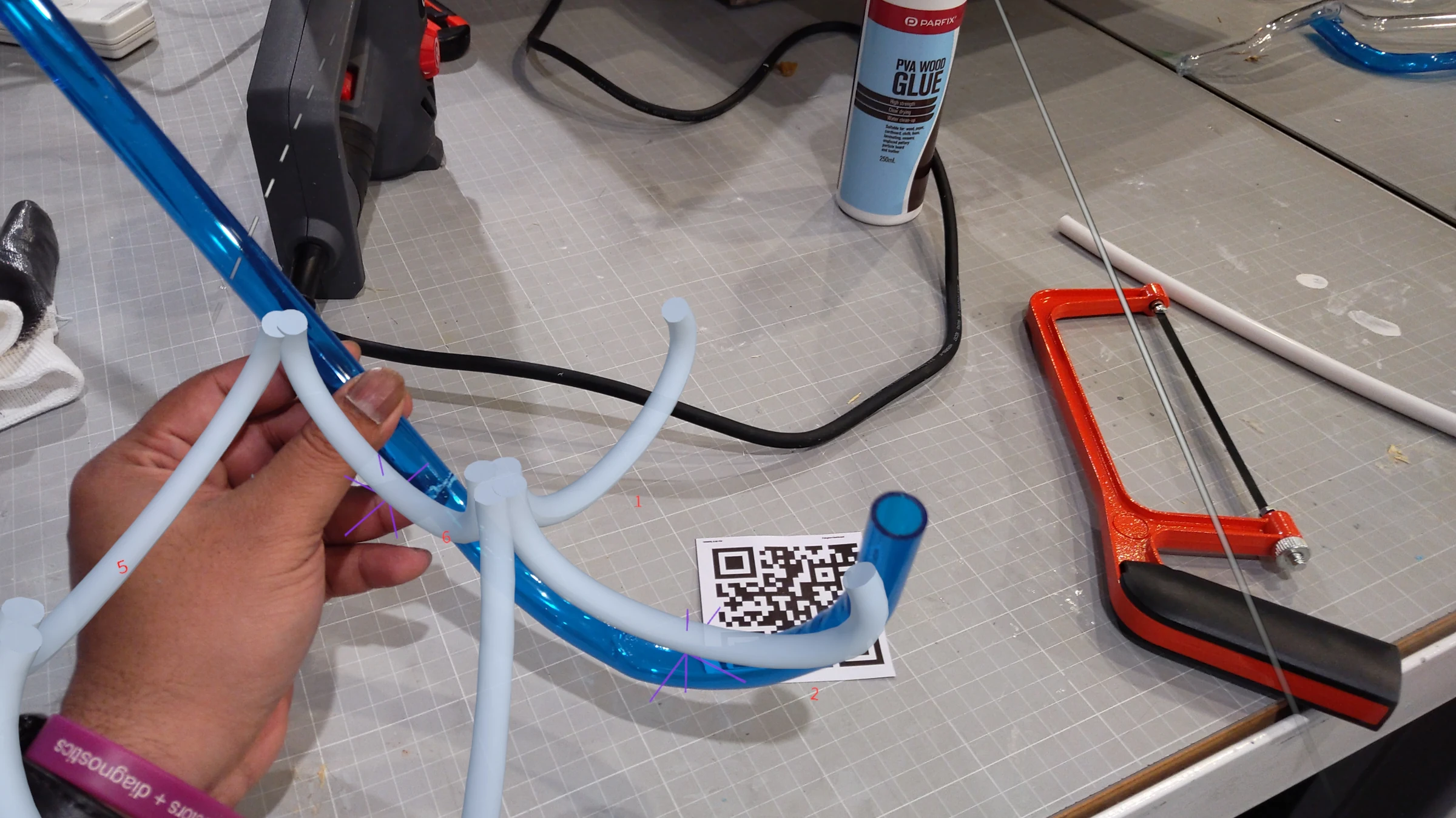 HoloLens capture: AR overlay projected onto workspace, holographic guides indicating tube positions and orientations at the start of assembly